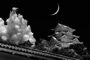 夜晚彎月與戲劇性雲層下的日本城堡。