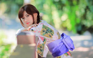 年輕女子穿著花卉和服靠在花園木欄杆上