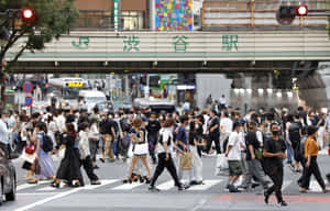 戴著口罩的行人在JR澀谷站天橋下穿過繁忙的東京街道。