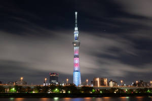 東京晴空塔在夜晚閃耀，城市燈光和水面倒影。