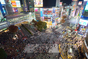 東京擁擠街道十字路口的夜間鳥瞰圖，帶有明亮的霓虹燈招牌。