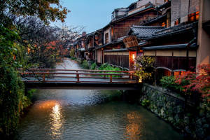 黃昏時分運河上的木橋，傳統日本房屋和秋葉。