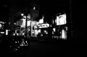 夜晚的城市街道，有發光的商店櫥窗和人們的黑色剪影。