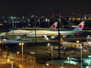 夜晚機場場景，背景有日本航空飛機和城市燈光。