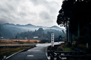 一條蜿蜒的道路穿過霧氣瀰漫的日本山脈，神社入口處有標誌。