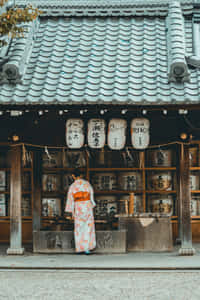 穿著花卉和服的人在日本神社，有瓦片屋頂和懸掛的燈籠。 — 日本 壁紙