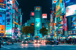 夜晚充滿活力的東京街道，帶有發光的霓虹燈招牌和繁忙的交通。 — 日本 壁紙