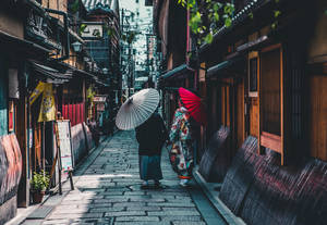 兩個穿著傳統日本服裝的人沿著一條狹窄的石頭小巷行走。