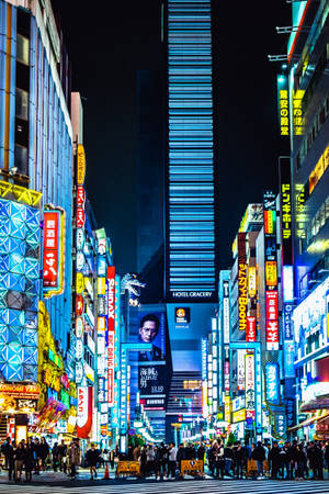 霓虹燈照亮嘅東京夜晚街道，人群同高聳嘅招牌。