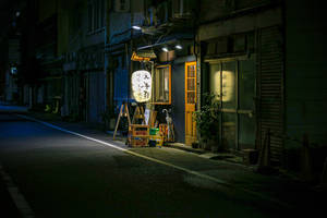 夜晚燈光昏暗的日本小巷，有發光的燈籠和關閉的商店門面。