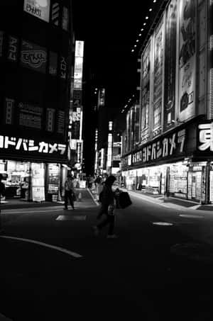 人在夜晚穿過霓虹燈照亮的東京街道，伴隨著發光的標誌。