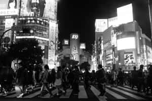 人群在夜晚繁忙的東京街道上，在明亮的霓虹燈牌下穿越。
