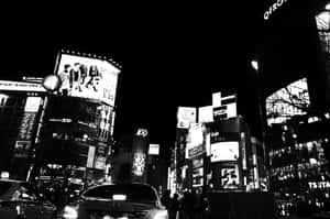 夜晚的東京街道，有明亮的廣告牌和汽車。