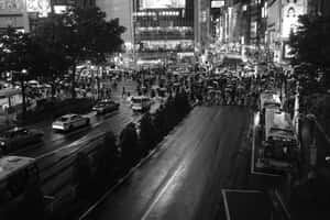 人群撐著傘在霓虹燈下穿過夜晚繁忙濕漉的城市街道。