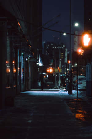 一個人在夜晚的積雪人行道上，在紅色交通燈下獨自行走。 — 月色夜空 壁紙