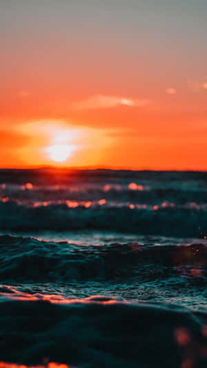 海洋上的夕陽，帶有發光的波浪和橙色天空 — 雲朵 壁紙