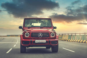 紅色 Mercedes G-Wagen 在日落時分於高速公路上奔馳，伴隨著戲劇性的雲層。