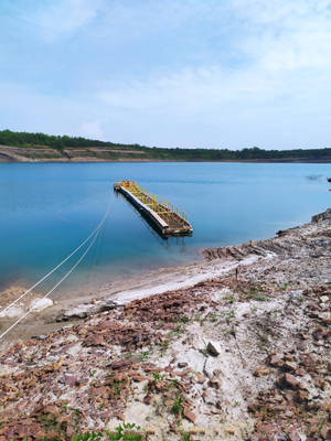 一條黃色碼頭從岩石海岸線延伸到平靜的藍色湖泊。