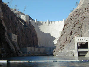 一座大型混凝土水壩坐落於岩石峽谷壁之間，下方平靜的水面。