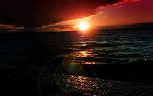 夕陽映照海面，帶有鏡頭光暈和碼頭剪影