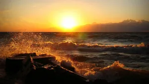 夕陽映照海洋,海浪拍打岩石