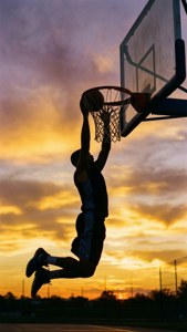 籃球運動員在充滿活力的日落天空下灌籃的剪影。