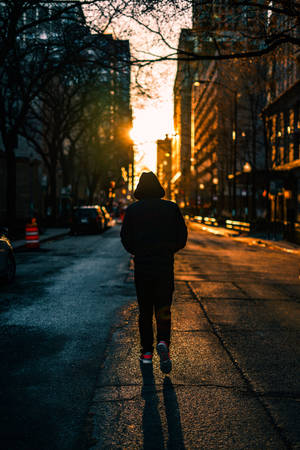 一個人獨自走在濕漉漉的城市街道上，金色夕陽。