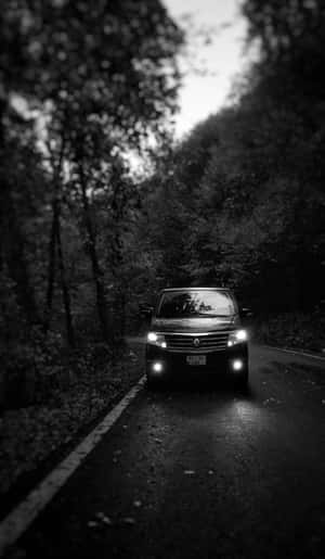 黑色SUV車頭燈照亮夜間森林道路。 — Huawei Pura X View 壁紙