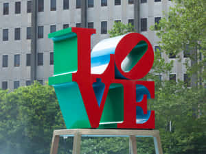 城市公園中色彩繽紛的LOVE雕塑，背景有樹木和建築物