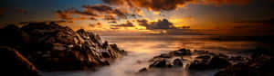 岩石海岸線上的夕陽與霧氣瀰漫的海浪