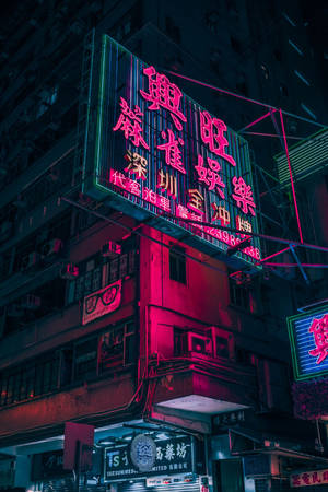 霓虹燈在夜間照亮密集的城市建築，呈現粉紅色和綠色色調。 — 霓虹 壁紙