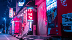 夜晚霓虹燈照亮的日本街道，商店關閉，有一台紅色自動販賣機。