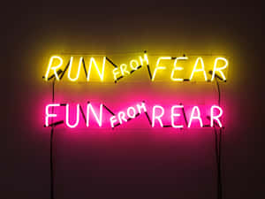 兩個霓虹燈牌，寫著 run from fear 和 fun from rear，在深色牆上。 — 螢光黃 壁紙