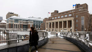 冬天在雪橋上走向大學建築的人。
