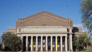 Cyrus Northrop Memorial Auditorium，柱子和旗幟，藍天下。