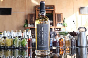 Tattersall Apple Brandy酒瓶放在吧檯上，配有雞尾酒杯和青檸裝飾。