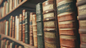 圖書館木架上的一排古董皮革書籍，帶有金色細節。 — 復古gif 壁紙
