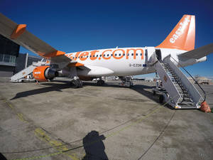易捷航空飛機停在機場閘口，附有登機梯和晴朗藍天。