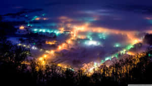 被雪覆蓋的村莊在夜晚透過霧氣閃爍著五彩燈光。