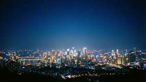 充滿活力的夜景城市天際線，閃爍的建築物和橋樑在繁星點點的天空下。