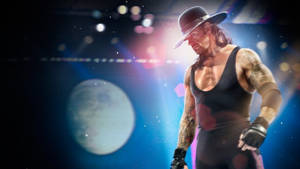 摔角手 The Undertaker 身穿黑色服裝和帽子，在舞台燈光下，背景為月亮