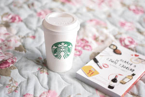 Starbucks咖啡杯和書放在花卉絎縫床罩上。