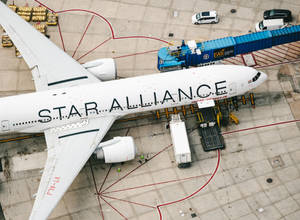 星空聯盟飛機停泊在機場閘口，配有登機橋和地面車輛。