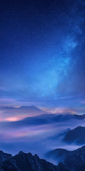 霧氣繚繞的山巒與發光雲層之上的星空之夜。 — Pixel 3 壁紙