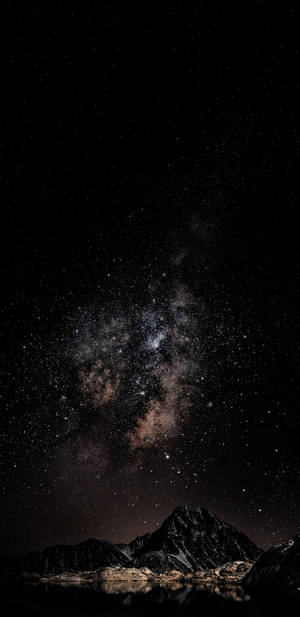 銀河星系位於山峰之上，倒映在夜晚的靜止水面。