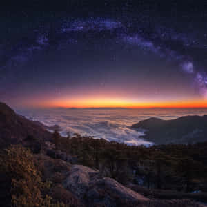 夜晚的山脊，下方有雲，上方有銀河