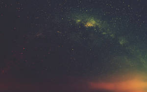 廣闊的夜空，星星和彩色星雲在地平線上方發光。