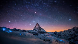 白雪覆蓋的山峰在紫色和橙色色調的星空暮色天空下。 — 超高清 GIF 壁紙