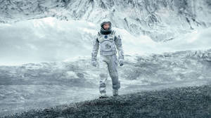 太空人站在灰色景觀中積雪的外星山脊上。 — 太空人 壁紙