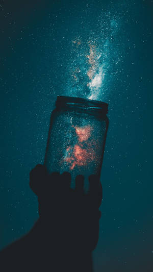 手拿著一個裝滿閃爍星星的罐子，背景是繁星點點的夜空。 — Galaxy Note 壁紙